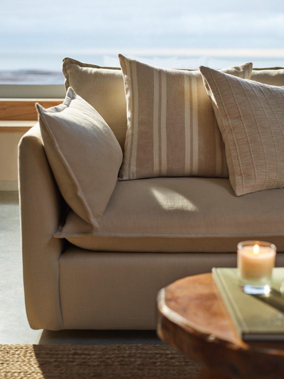 a couch with pillows and a candle on a table