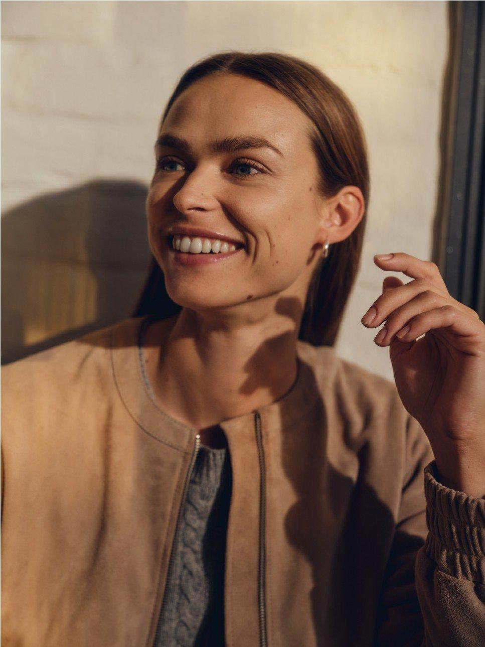 a woman smiling while holding a cell phone to her ear