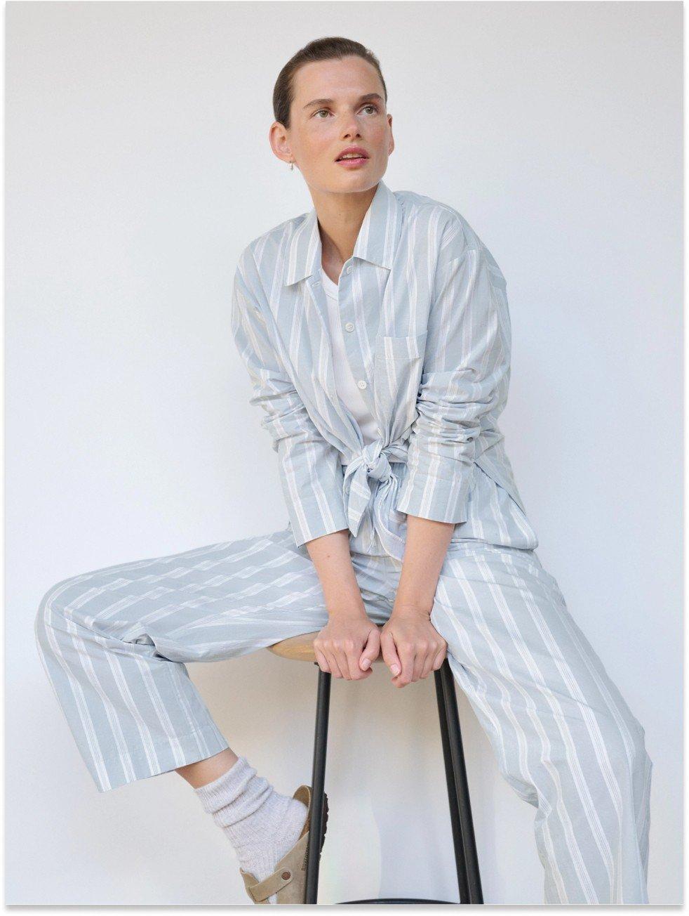 a woman in a striped pajama top sitting on a stool