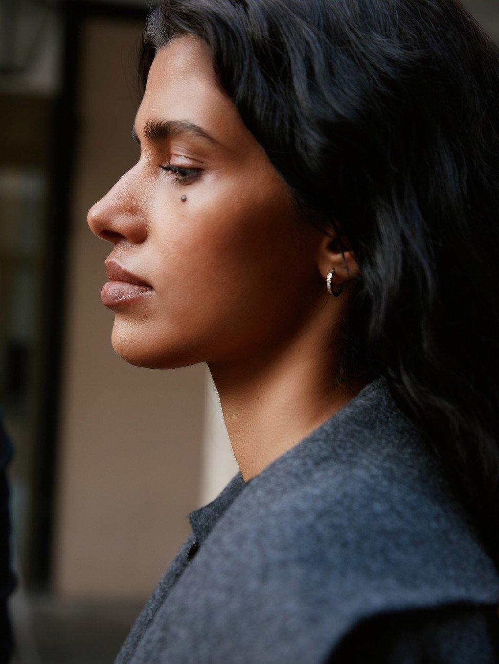 a woman with long black hair looking down while using a cell phone