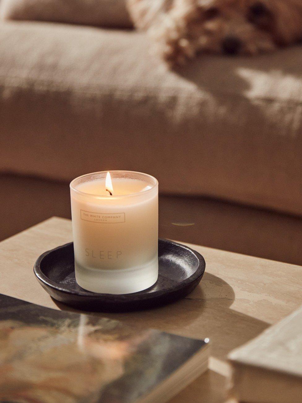 a candle on a table next to a dog and a book