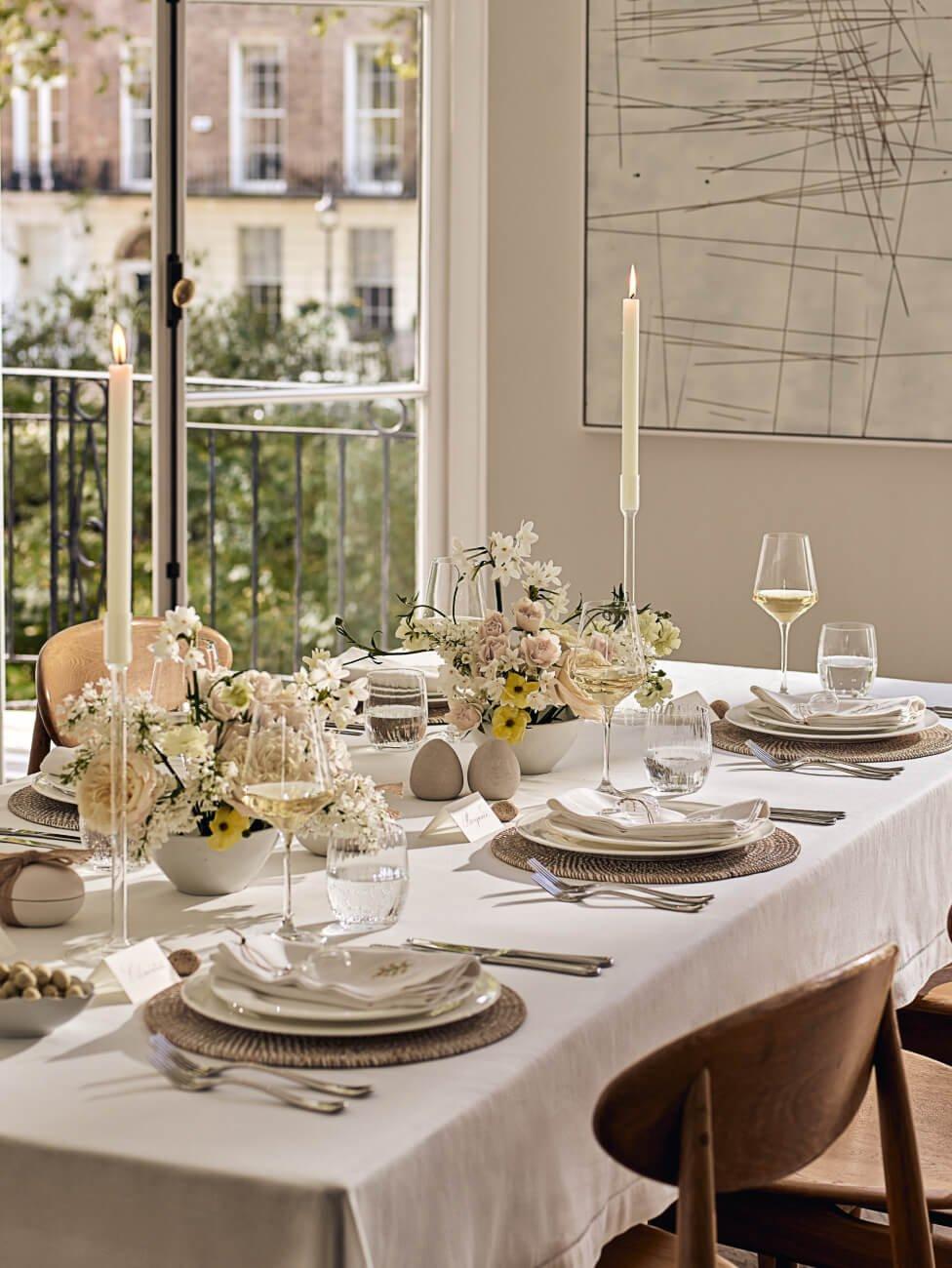 a table set with white plates and silverware on a balcony