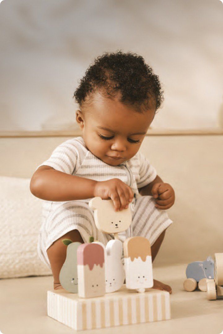 a baby playing with wooden blocks on a white surface