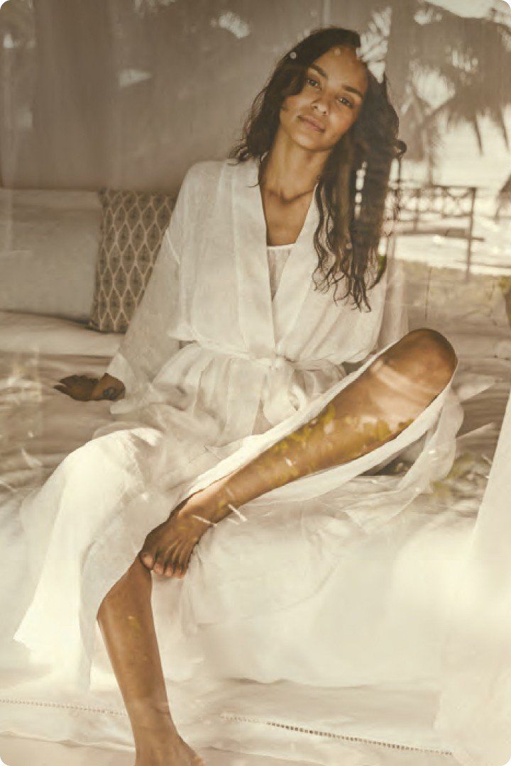 a woman in a white robe sitting on a bed