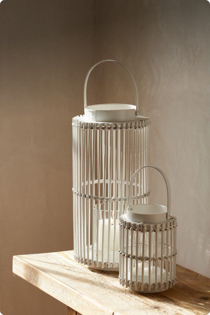 two white lanterns on a wooden table with a candle inside