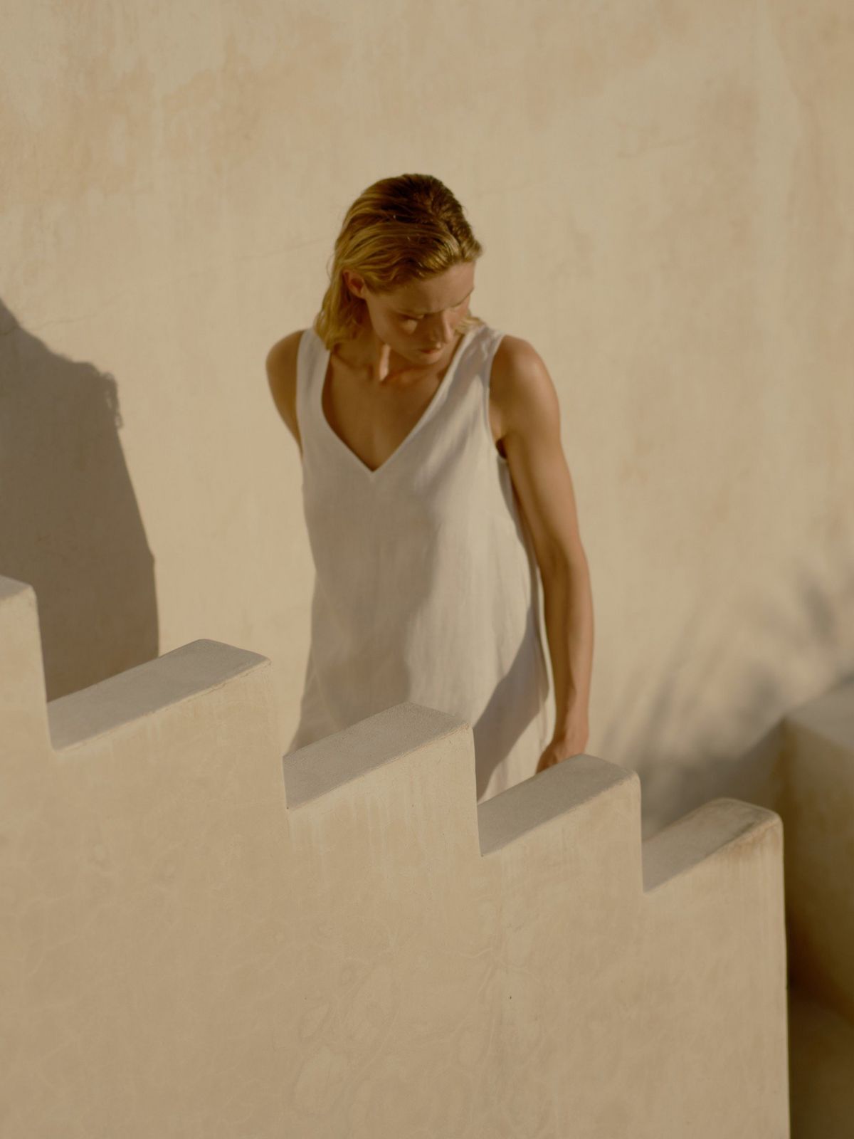 a woman leaning against a wall with her hands on her hips