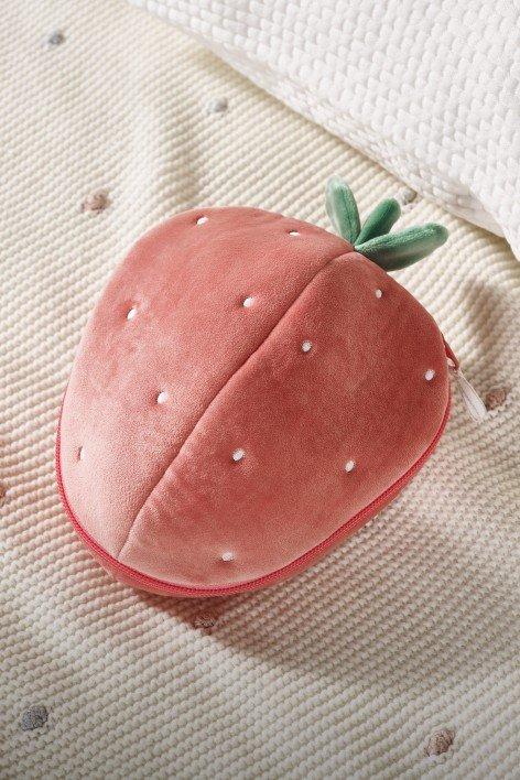 a strawberry shaped pillow on a bed with a white sheet