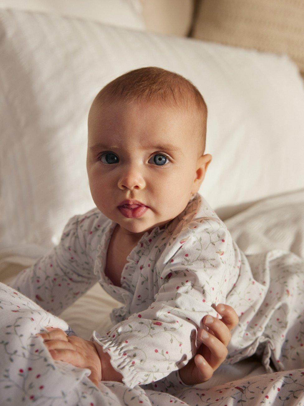 a baby laying on a bed with a woman holding it