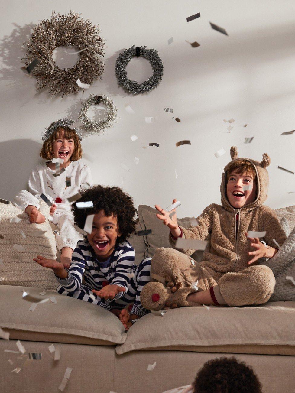 a group of children sitting on a couch with confetti falling from the ceiling