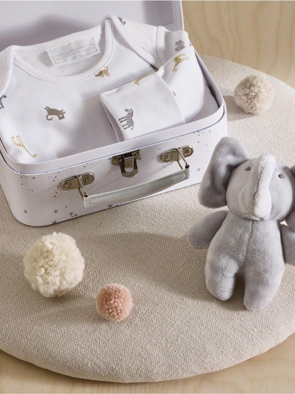 a white baby suit with a stuffed elephant sitting next to it