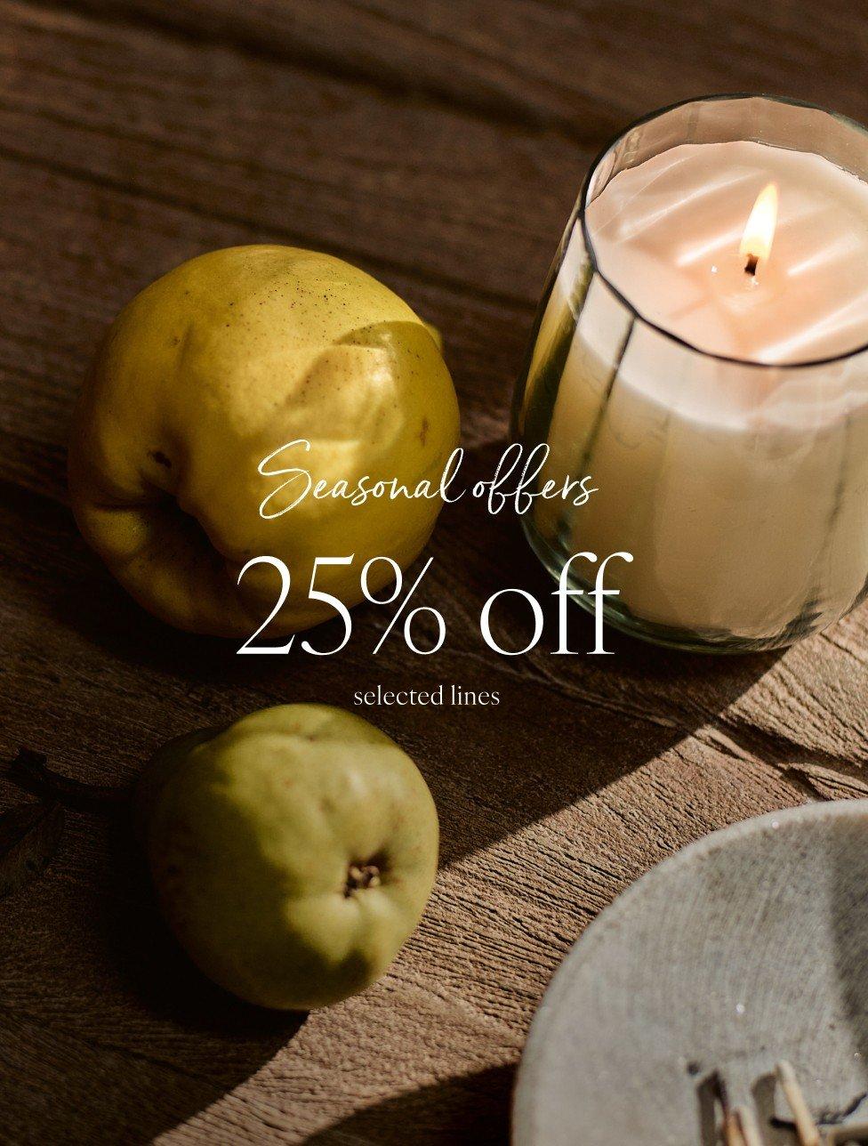 a candle and apples on a table with a 25% off sign