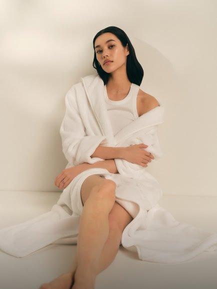 a woman in a white robe sitting on a white floor