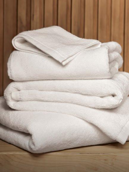 a stack of white towels sitting on a stool next to a plant