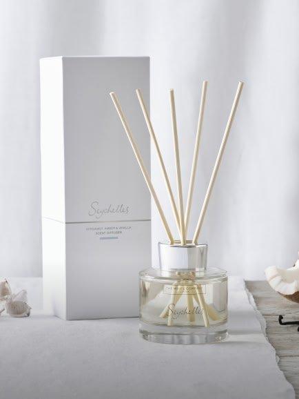 a white reed diffuser with a box and some shells