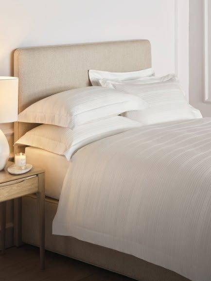 a bed with white sheets and pillows in a bedroom