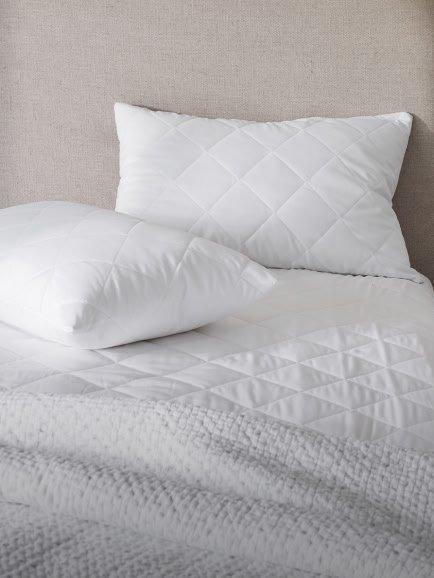 a white pillow on a bed with a white headboard