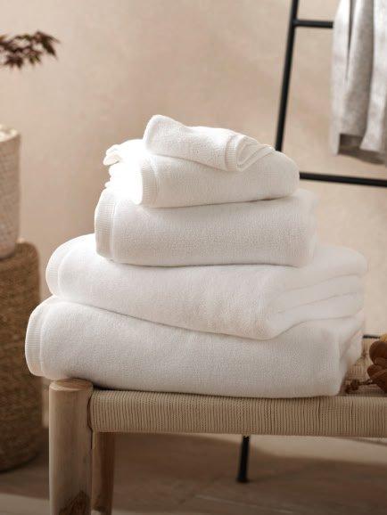 a stack of white towels sitting on a stool next to a bathtub