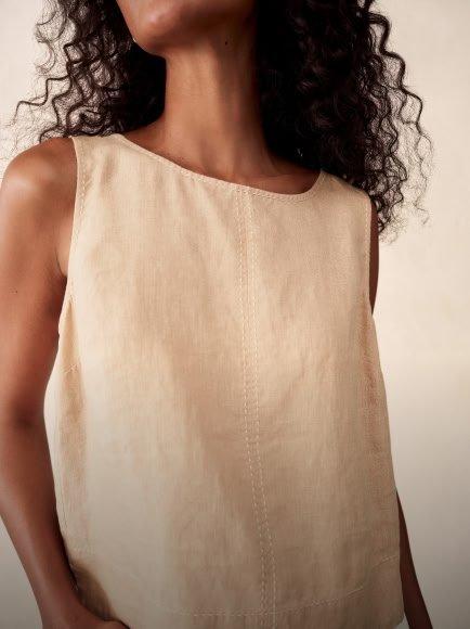 a woman with curly hair wearing a white top and a black hat