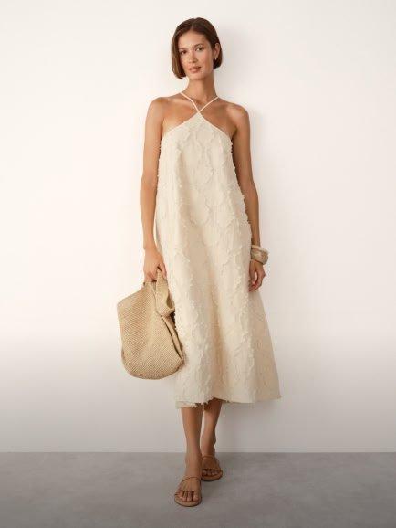 a woman in a white dress and straw bag