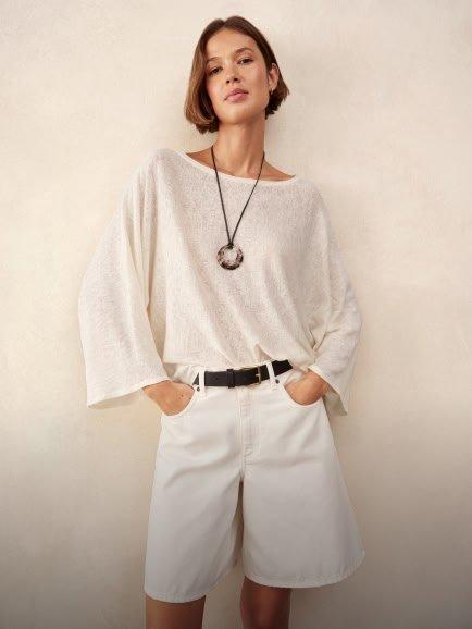 a woman in white shorts and a white top posing for a photo
