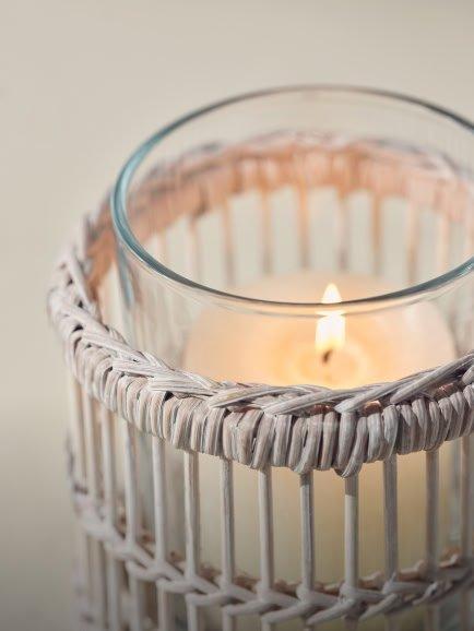 a candle in a wicker candle holder with a white candle