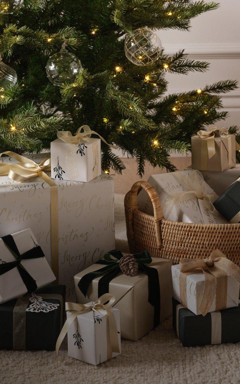a basket filled with presents under a christmas tree