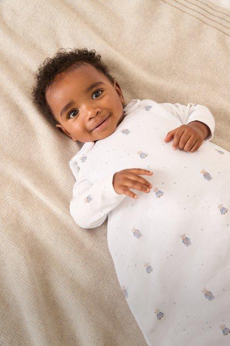 a baby laying on a bed with a white sheet