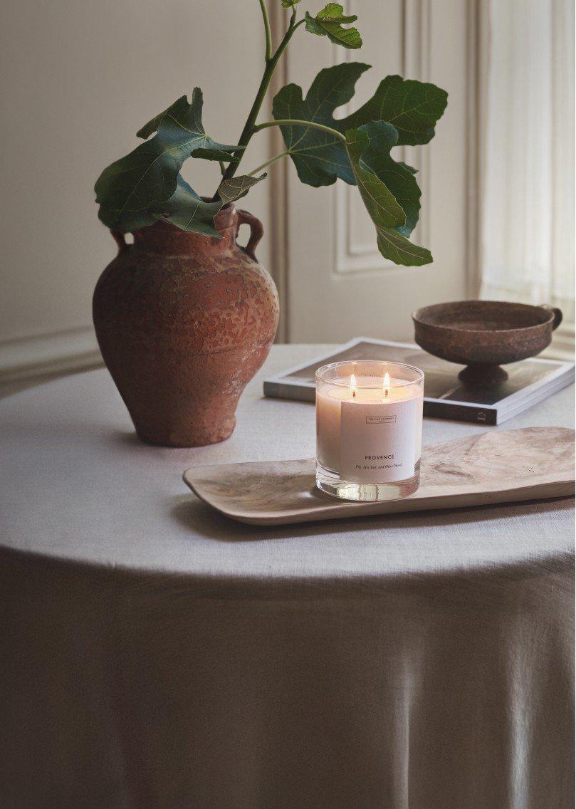 a candle on a table next to a vase and a plant
