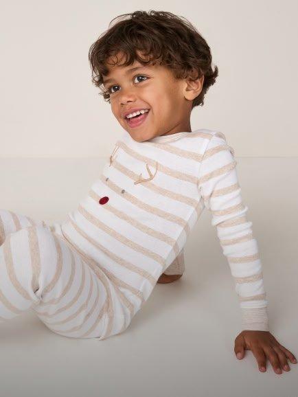 a young boy in striped pajamas smiling while laying on the floor