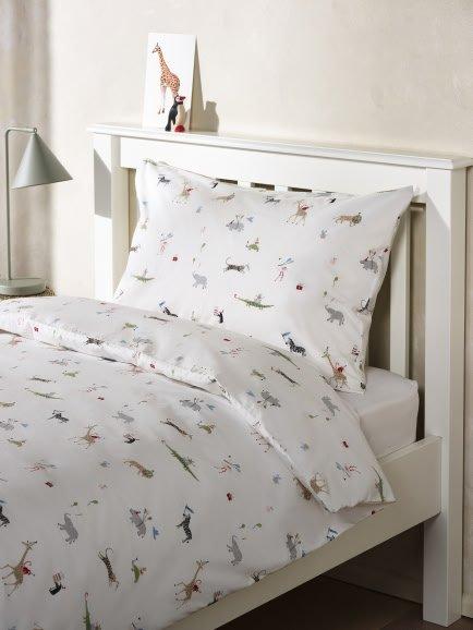 a white bed with a white comforter and a giraffe pillow