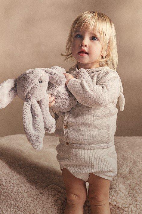 a little girl holding a stuffed animal on a bed