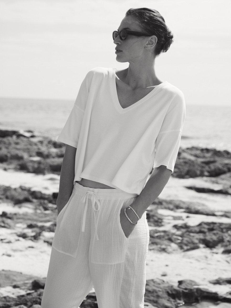 a woman on the beach wearing a white t shirt and sunglasses