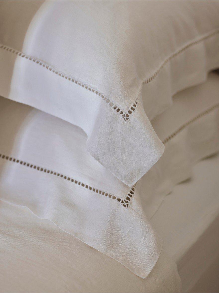 a close up of a bed with white sheets and pillows