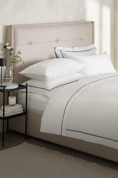 a bed with white sheets and pillows in a bedroom