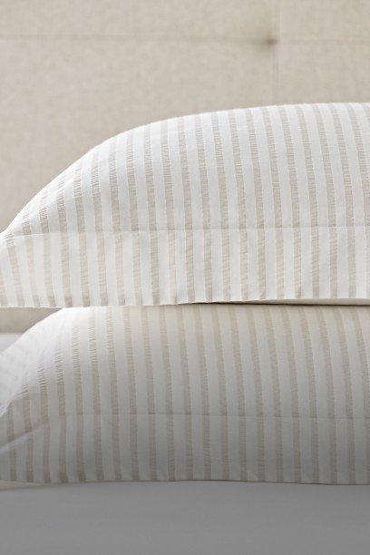 two pillows on a bed with a white and gray striped blanket