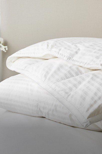 a bed with a white comforter and pillows on top of it