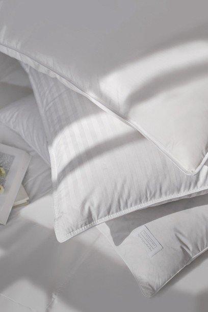 a pile of pillows on a bed with a book on top