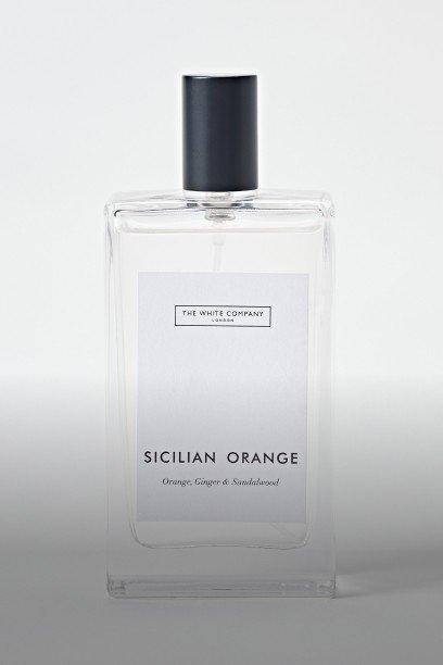 a white bottle of perfume next to a white box