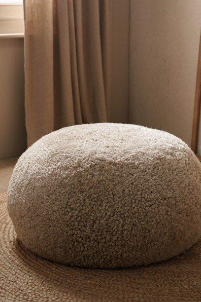 a large round cushion sitting on a rug in front of a window