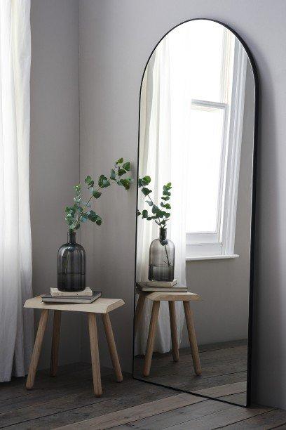 a mirror with a potted plant on a table in front of it
