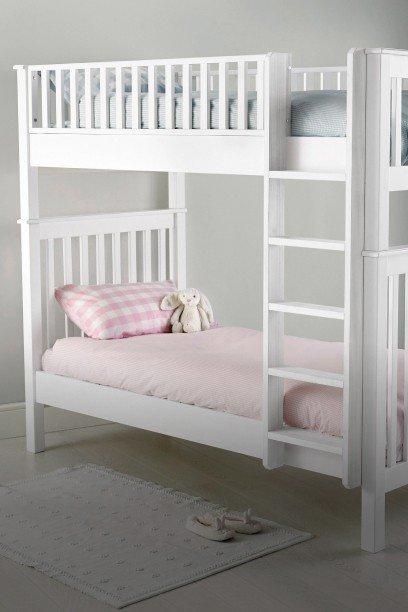 a bed with a white blanket and a small doll house
