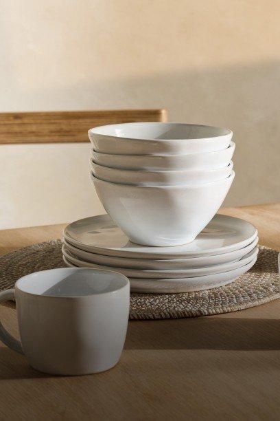 a stack of white plates and cups on a table