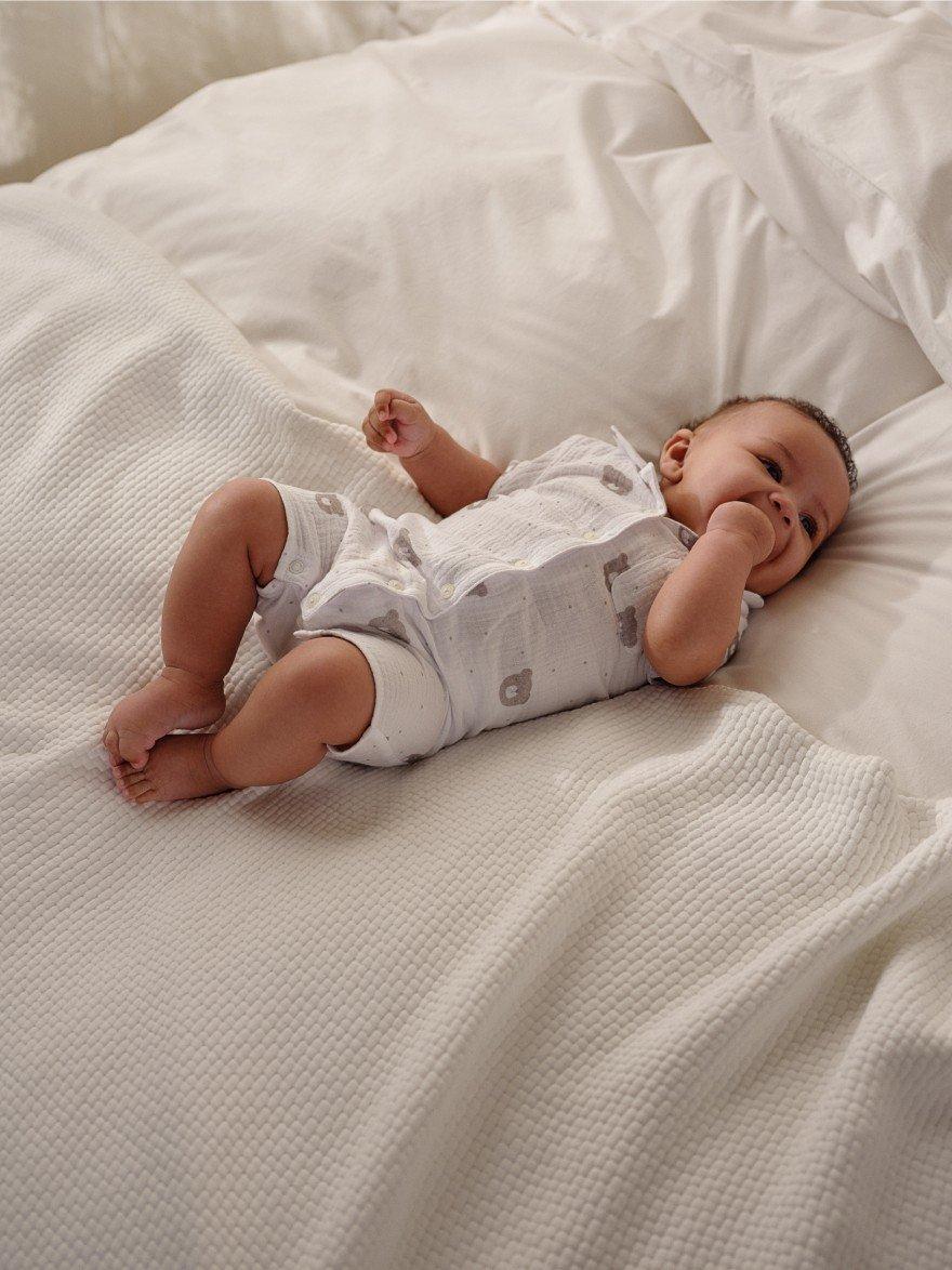 a baby laying on a bed with a white sheet