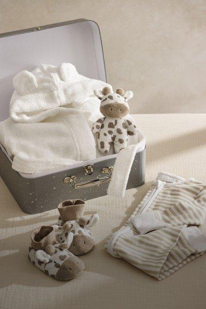 a suitcase with a stuffed giraffe and baby clothes on top
