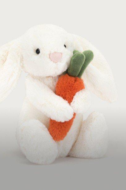 a stuffed bunny holding a carrot in its mouth on a white background