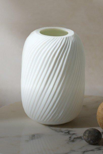 a white vase with a plant in it on a table