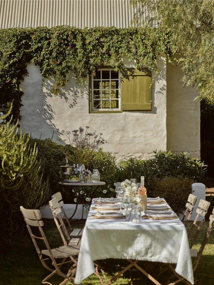 a table set for a meal in a backyard with a white house