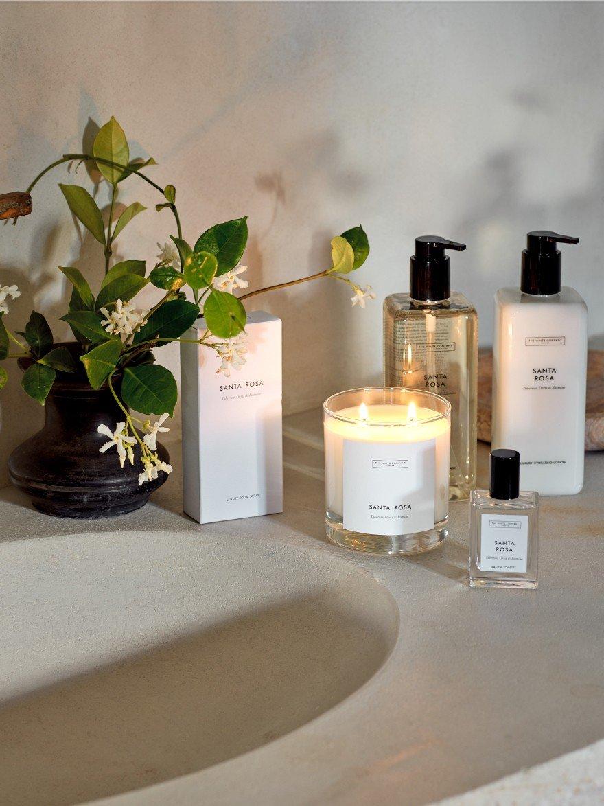 a couple of bottles of lotion sit on a counter next to a candle
