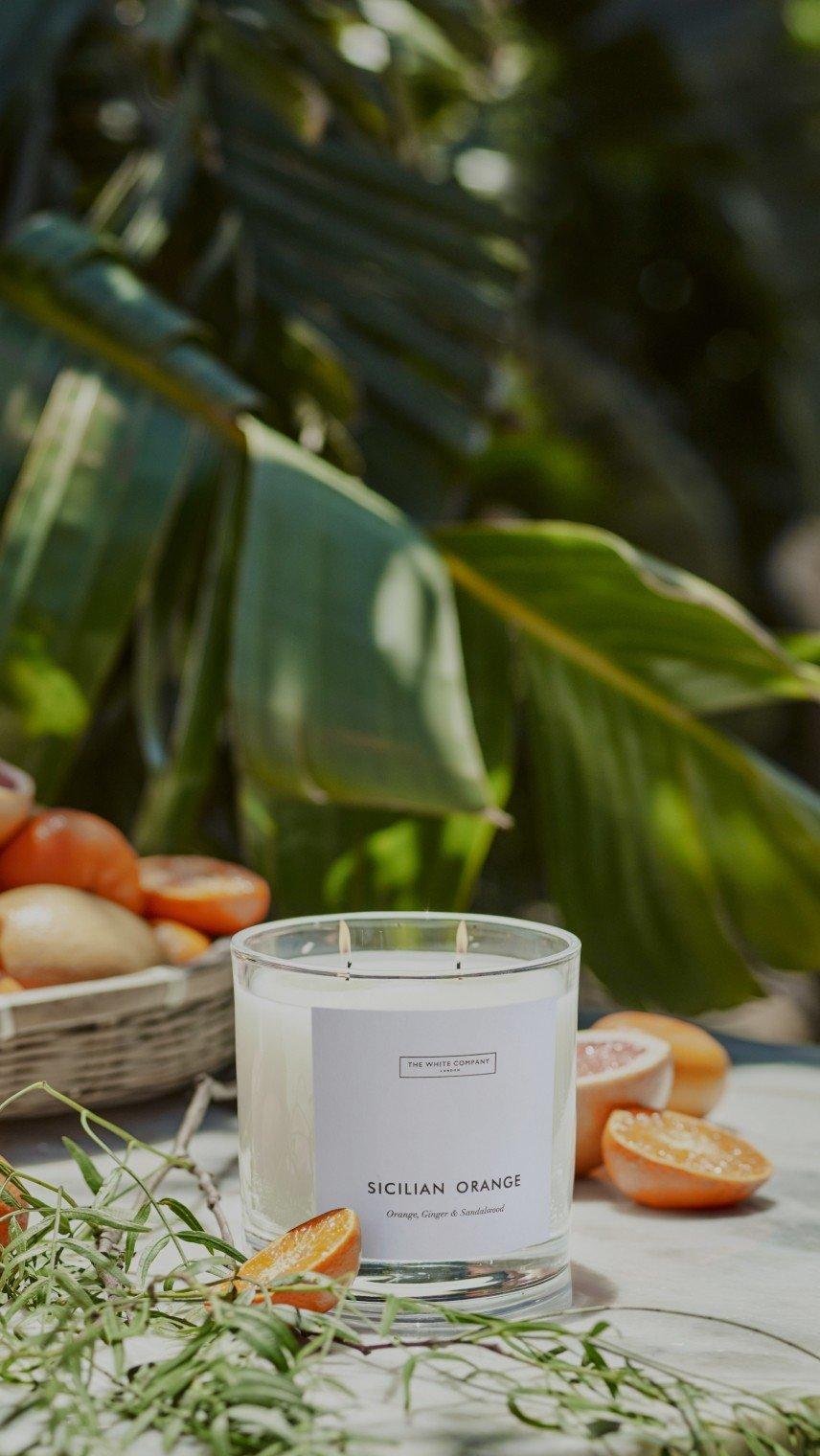 a candle on a table with oranges and other fruit on it