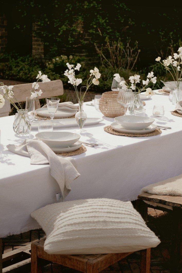 a table set with white plates and white flowers on it